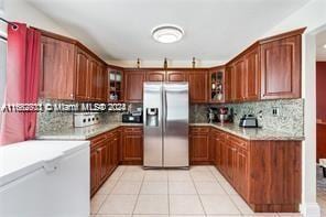 kitchen with light tile patterned flooring, stainless steel refrigerator with ice dispenser, and tasteful backsplash