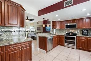 kitchen featuring backsplash, kitchen peninsula, stainless steel appliances, decorative light fixtures, and light tile patterned floors