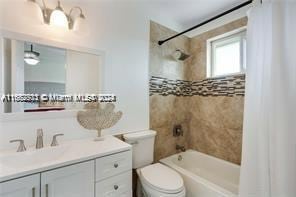 full bathroom with toilet, shower / bathtub combination with curtain, and vanity