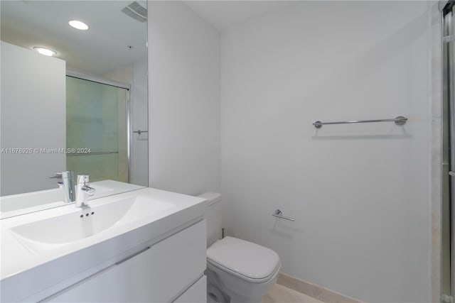 bathroom featuring toilet, a shower with shower door, and vanity