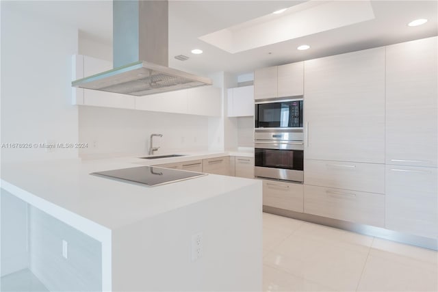 kitchen featuring black appliances, sink, light tile patterned flooring, island exhaust hood, and kitchen peninsula