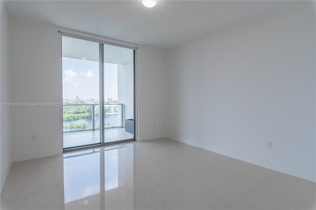 tiled empty room featuring a water view and floor to ceiling windows