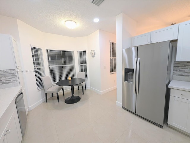 kitchen with tasteful backsplash, visible vents, stainless steel appliances, and light countertops