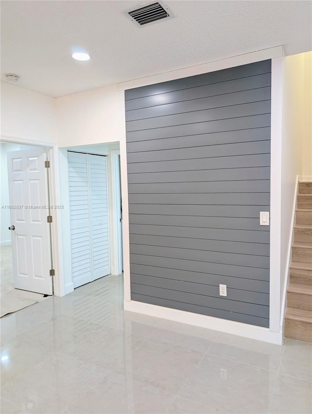 interior space featuring visible vents, recessed lighting, wood walls, baseboards, and stairs