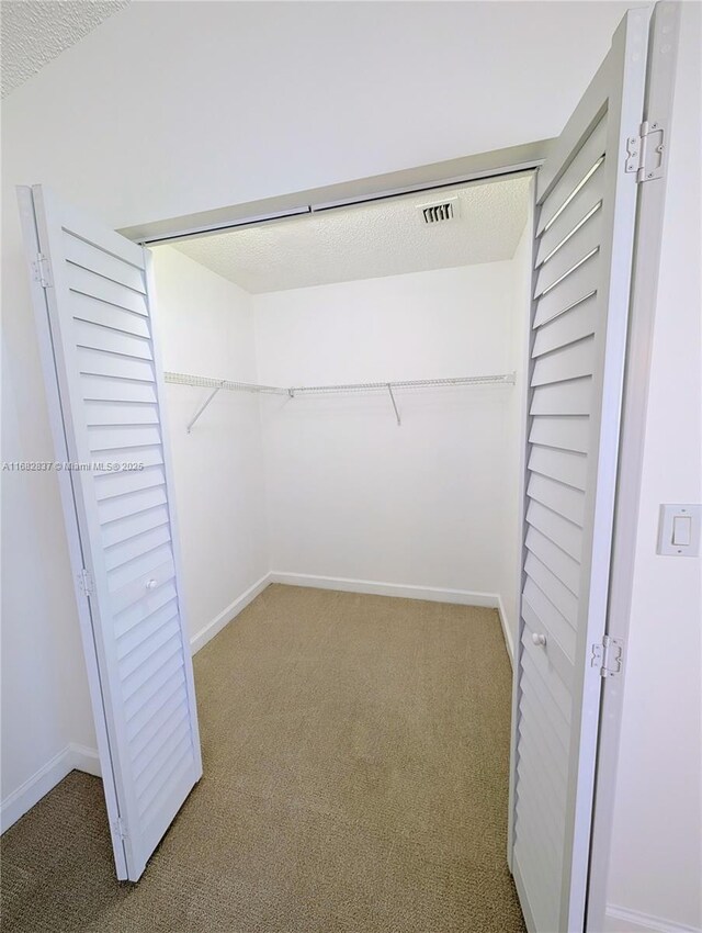 unfurnished bedroom featuring light colored carpet and multiple closets