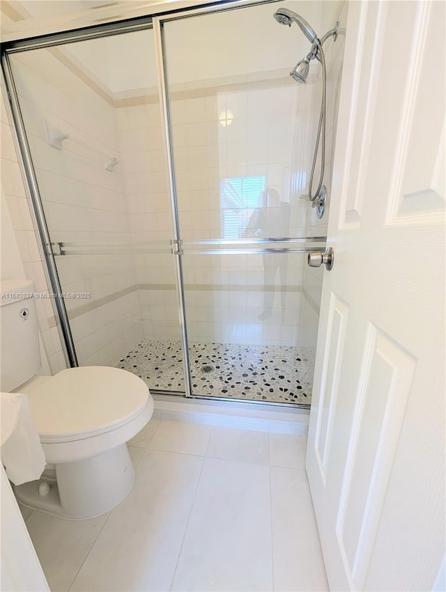 bathroom with toilet, a shower stall, and tile patterned flooring