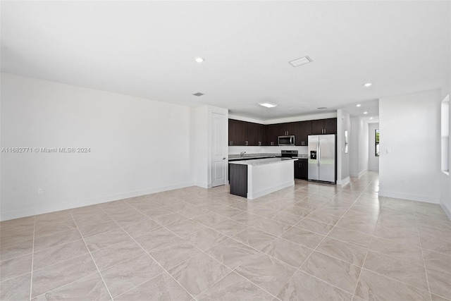 kitchen with dark brown cabinets, a kitchen island, appliances with stainless steel finishes, light tile patterned flooring, and sink