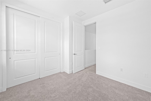 unfurnished bedroom featuring light colored carpet and a closet