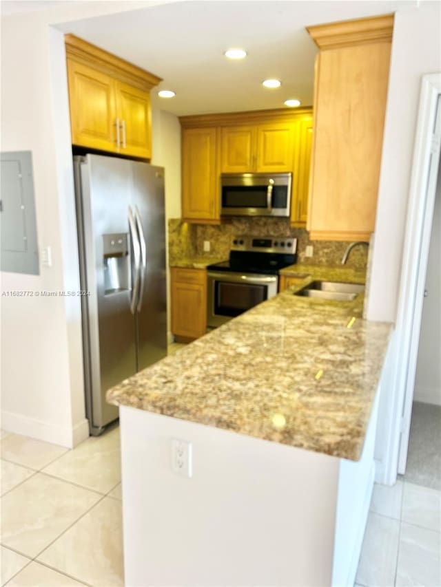 kitchen featuring appliances with stainless steel finishes, kitchen peninsula, light stone countertops, and sink