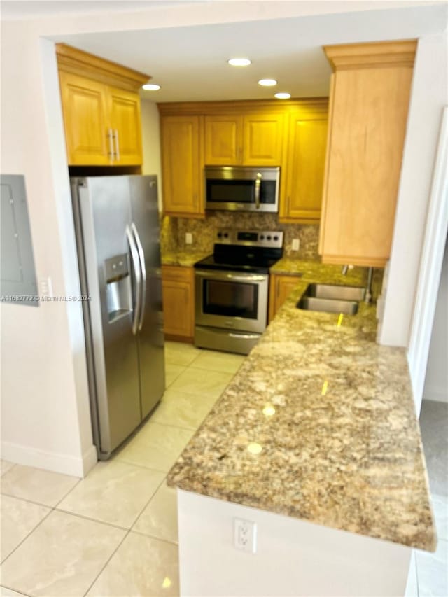 kitchen featuring tasteful backsplash, light tile patterned floors, light stone countertops, sink, and stainless steel appliances