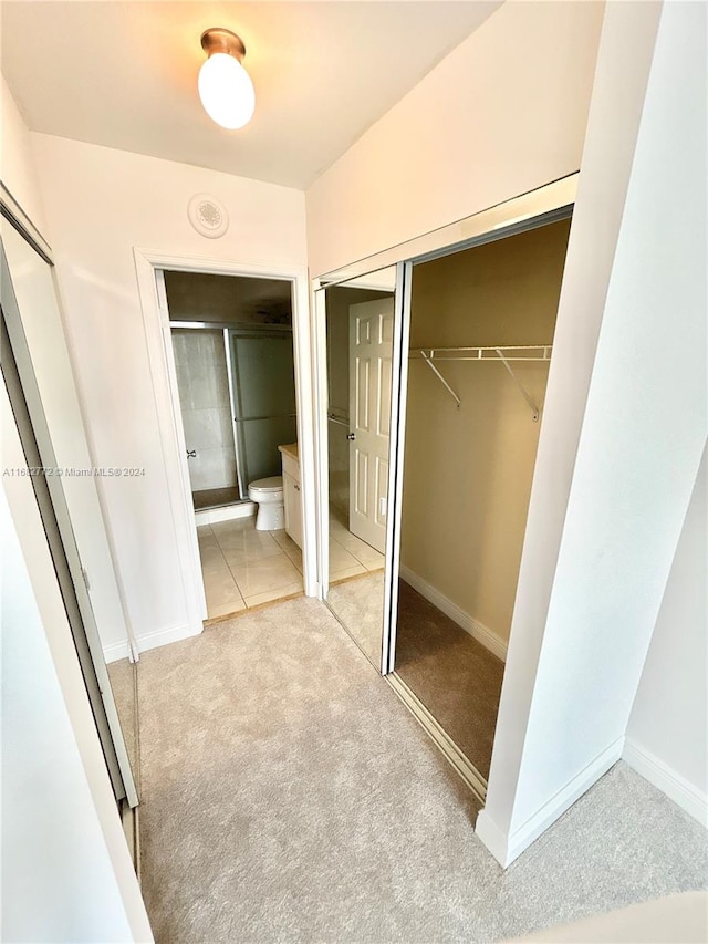 unfurnished bedroom with a closet, connected bathroom, and light colored carpet