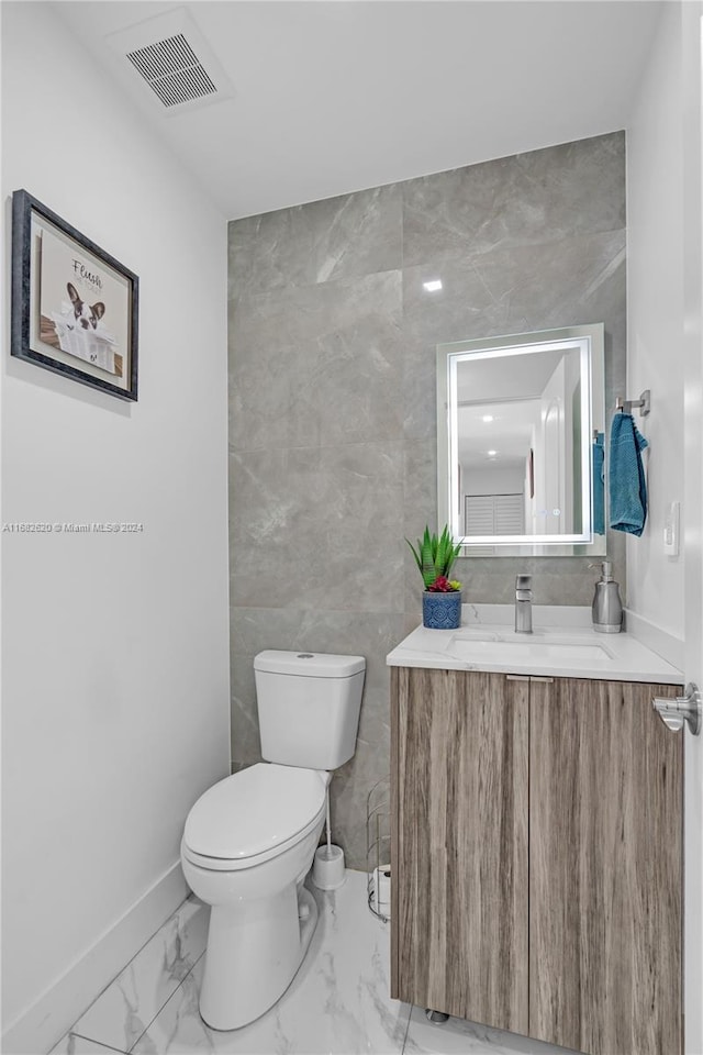 bathroom featuring vanity, toilet, and tile walls