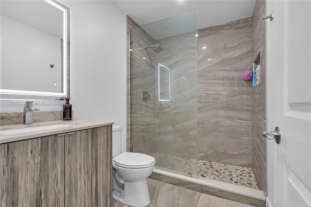 bathroom featuring vanity, toilet, and a tile shower