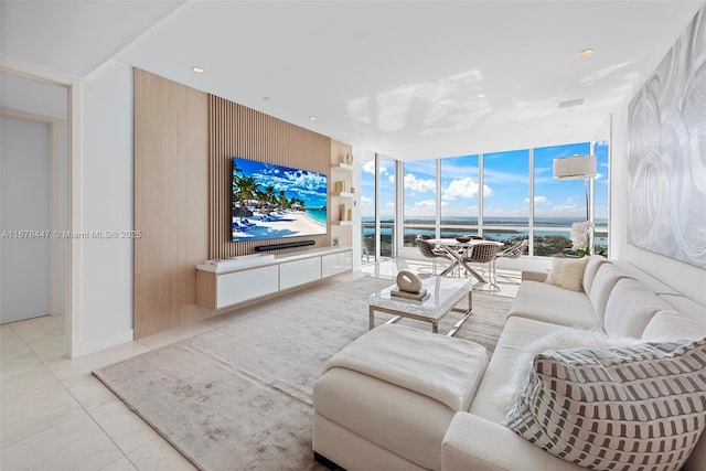 living room featuring floor to ceiling windows, light tile patterned flooring, and a wall unit AC