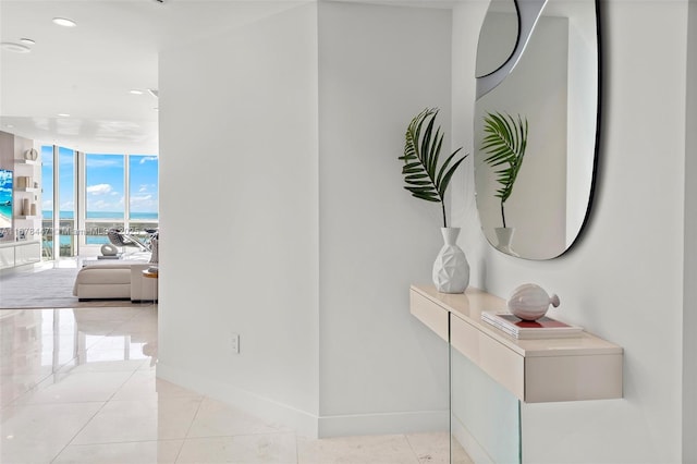 hallway with light tile patterned flooring and a wall of windows