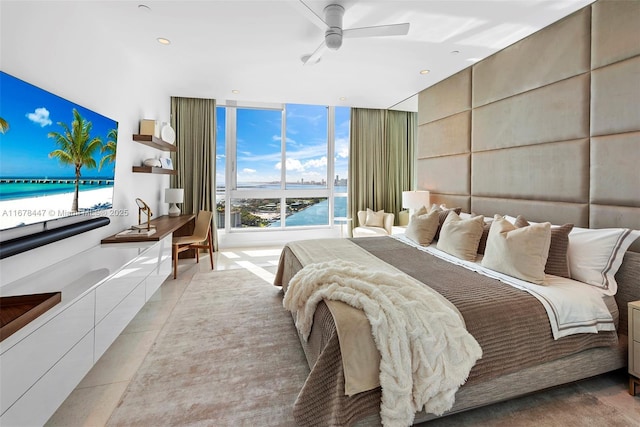 bedroom featuring expansive windows, ceiling fan, and a water view