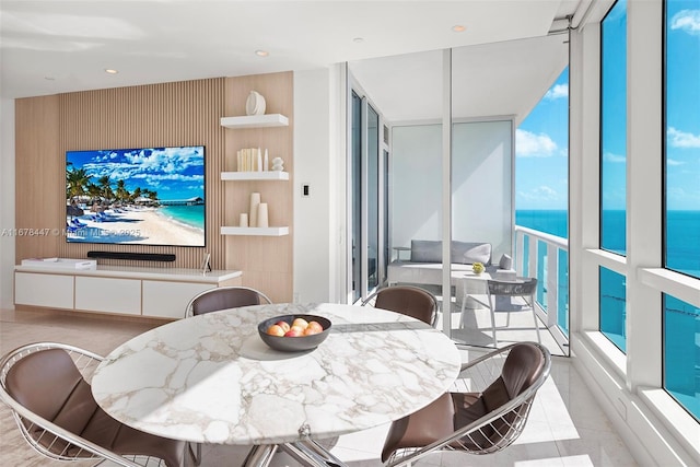 tiled dining area featuring a water view and a wall of windows