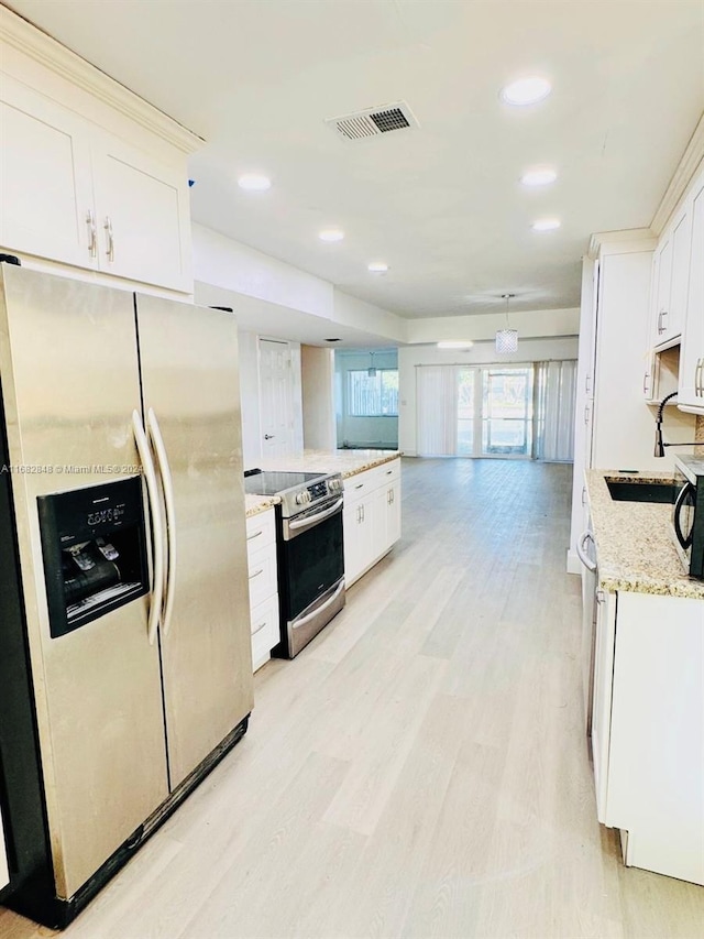 kitchen featuring light stone countertops, light hardwood / wood-style flooring, white cabinets, and appliances with stainless steel finishes