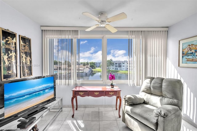 sitting room featuring ceiling fan, a water view, and light tile patterned floors