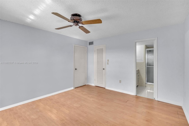 unfurnished bedroom with light hardwood / wood-style flooring, a textured ceiling, ensuite bath, and ceiling fan