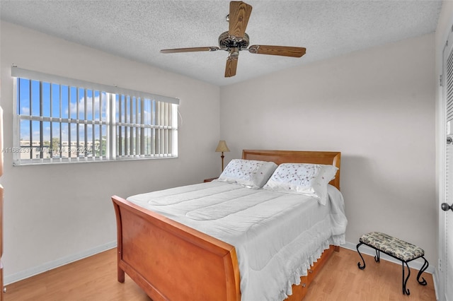 bedroom featuring ceiling fan, a textured ceiling, and light wood-type flooring