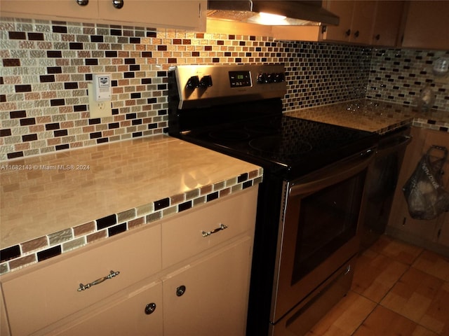 kitchen with white cabinetry, tasteful backsplash, wall chimney exhaust hood, and stainless steel range with electric cooktop