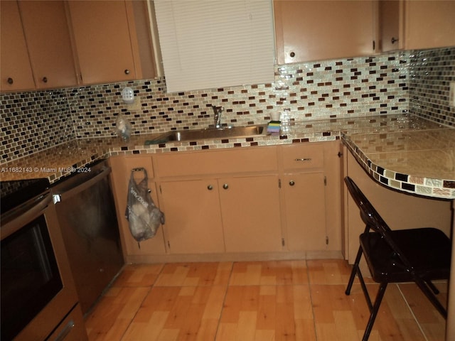 kitchen featuring sink, backsplash, appliances with stainless steel finishes, and light hardwood / wood-style flooring