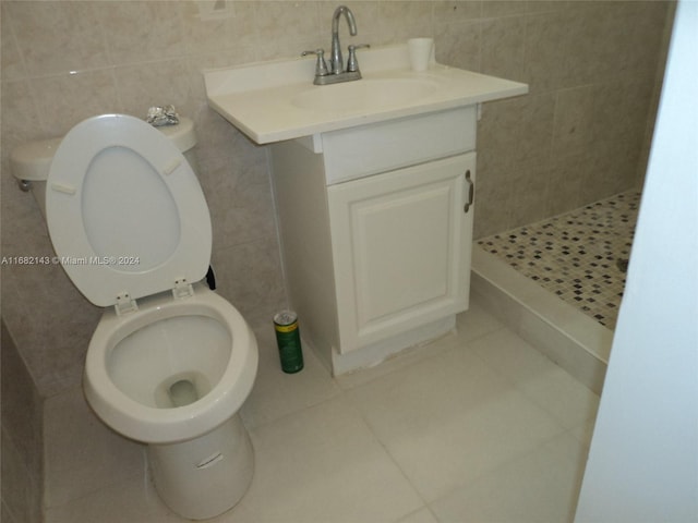 bathroom featuring toilet, tile walls, walk in shower, vanity, and tile patterned flooring