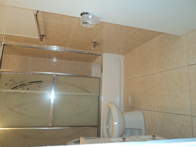 bathroom with toilet and bath / shower combo with glass door