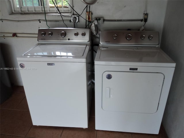 laundry area with washer and clothes dryer and dark tile patterned flooring