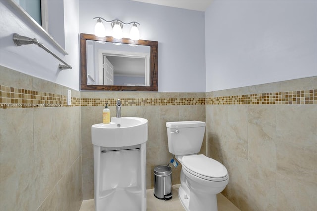 bathroom with toilet, vanity, and tile walls