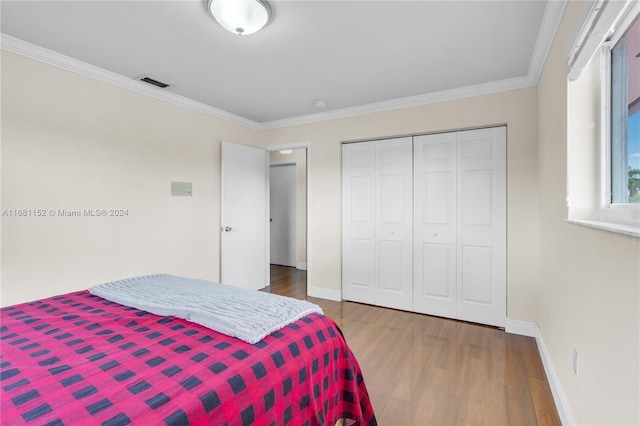 bedroom featuring a closet, hardwood / wood-style flooring, and crown molding