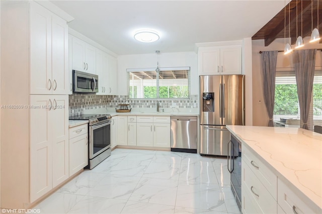 8135 SW 136th St, Pinecrest, FL 33156 - kitchen featuring appliances with stainless steel finishes, backsplash, light marble finish flooring, white cabinetry, and light stone countertops
