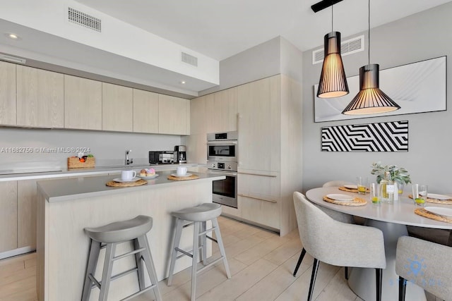 kitchen featuring a breakfast bar area, stainless steel double oven, a center island, and decorative light fixtures