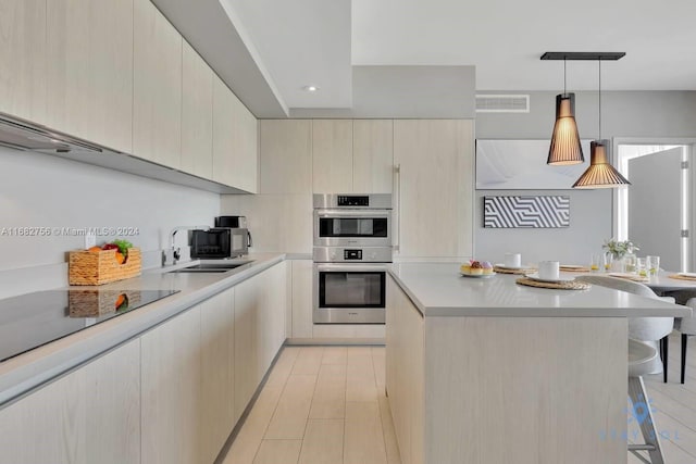 kitchen with sink, double oven, a kitchen breakfast bar, and decorative light fixtures