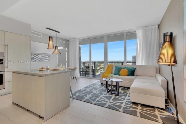 kitchen featuring stainless steel oven, a center island, pendant lighting, and a wall of windows