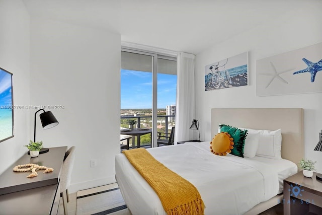 bedroom with hardwood / wood-style flooring, multiple windows, a wall of windows, and access to exterior