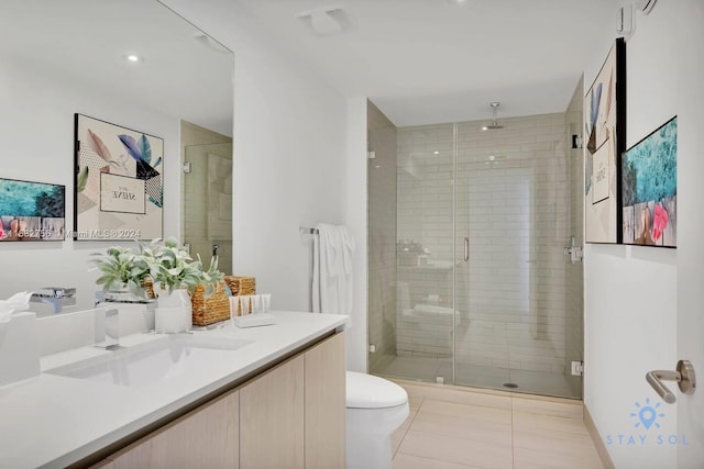 bathroom with a shower with door, vanity, toilet, and tile patterned flooring