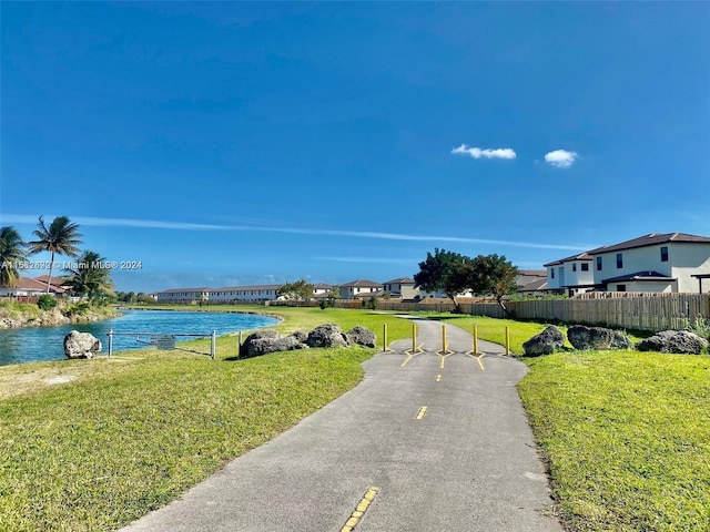 view of property's community with a water view and a lawn