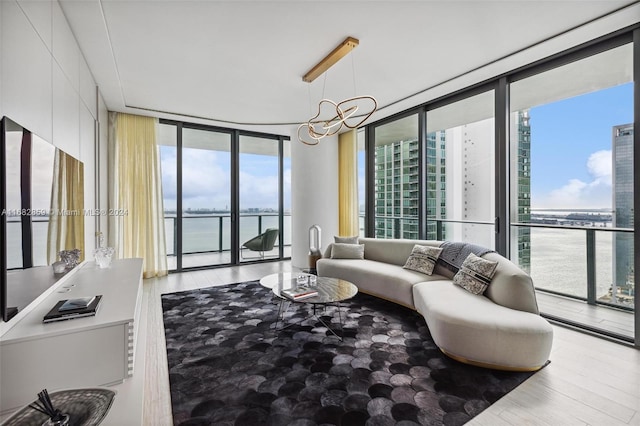 living room featuring a water view, hardwood / wood-style flooring, expansive windows, and a chandelier