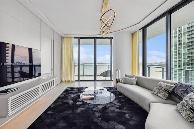 living room featuring light hardwood / wood-style floors, a wall of windows, a chandelier, and a water view