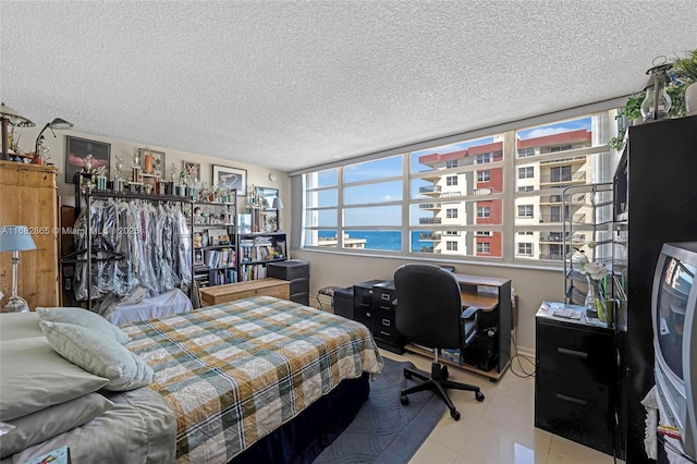 bedroom with light tile patterned floors, a textured ceiling, and a water view