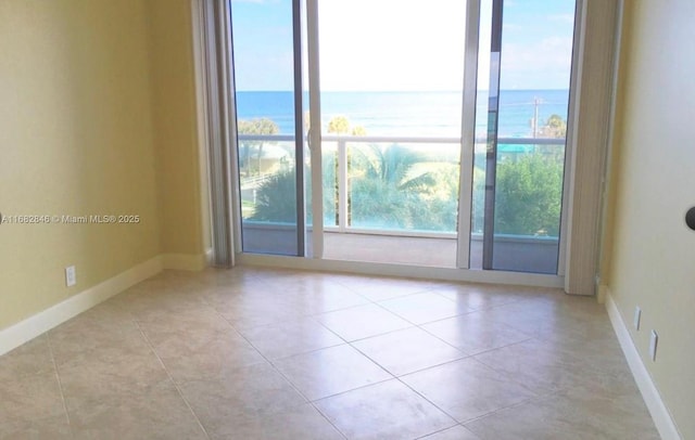 spare room with a water view, baseboards, and tile patterned floors