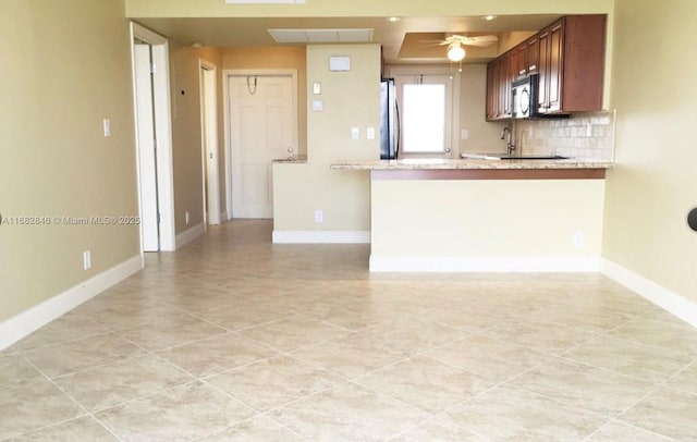 kitchen with tasteful backsplash, stainless steel refrigerator, kitchen peninsula, ceiling fan, and light stone countertops