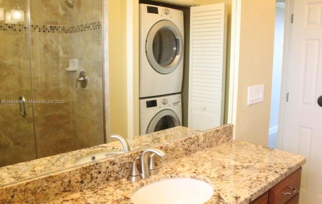 bathroom featuring vanity, a shower with door, and stacked washer / dryer