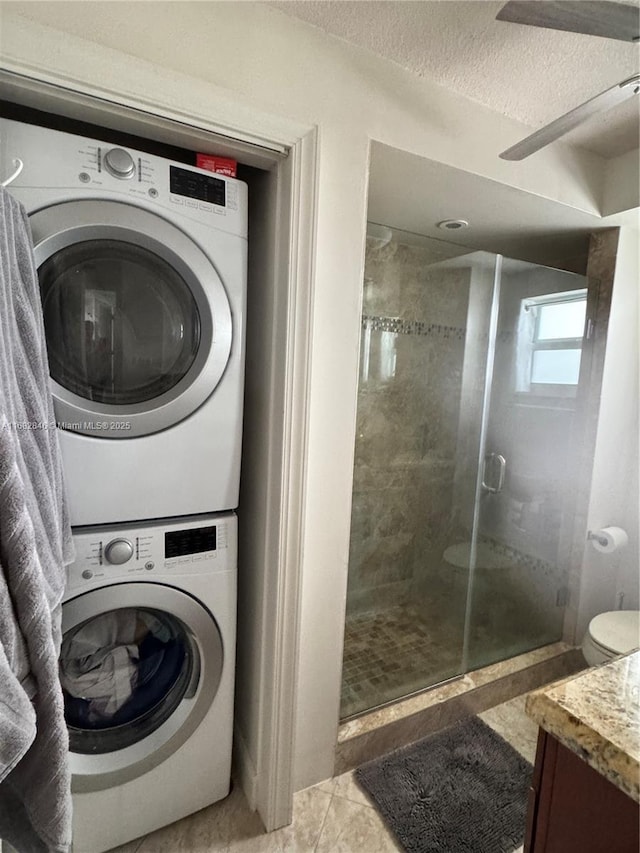 laundry area with laundry area, a textured ceiling, light tile patterned floors, and stacked washer / dryer