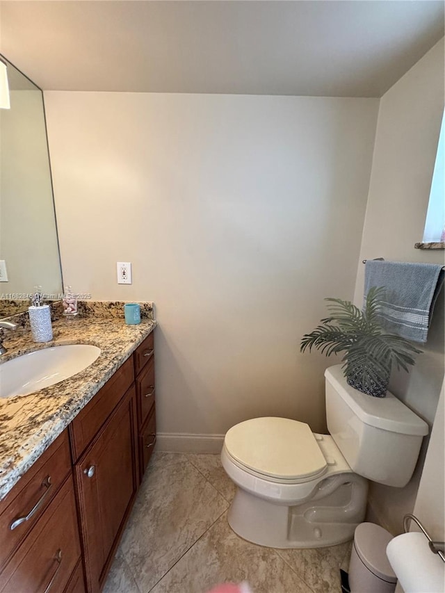 bathroom featuring toilet, baseboards, and vanity