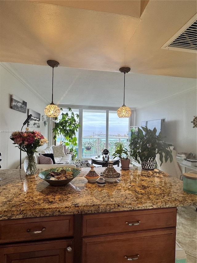 kitchen featuring hanging light fixtures, stone counters, visible vents, and crown molding