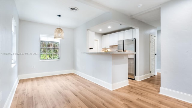 kitchen featuring white cabinetry, kitchen peninsula, pendant lighting, and light hardwood / wood-style floors