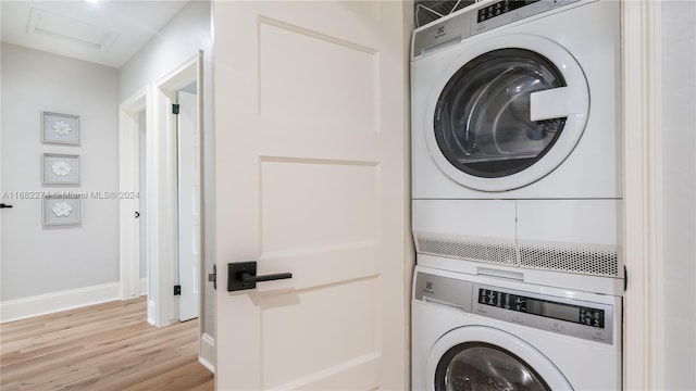 clothes washing area featuring light wood-type flooring and stacked washer and clothes dryer